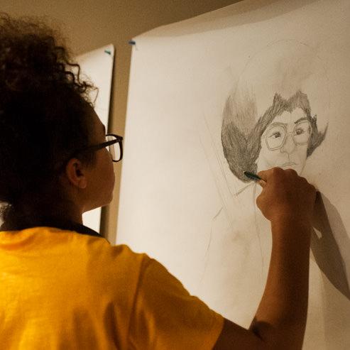 The two artists draw a series of portraits along a wall at the Peabody.