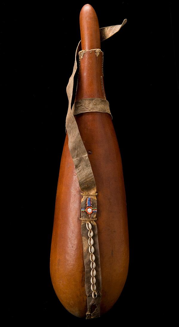 YPM ANT 250031: Large calabash container; attached leather carrying strap decorated with cowrie shells.  Masai, Kenya