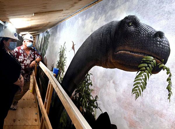 Peabody Museum staff next to Brontosaurus on The Age of Reptiles mural by Rudolph Zallinger