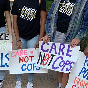 Students holding signs which reach 'Care, not cops'
