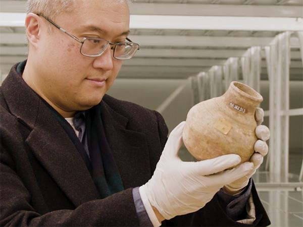 Andrew Koh inspecting a ceramic vessel